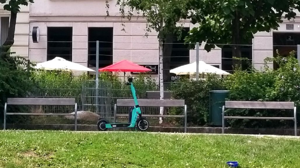 ein grüner Scooter lehnt an einer Bank im Hamerlingpark